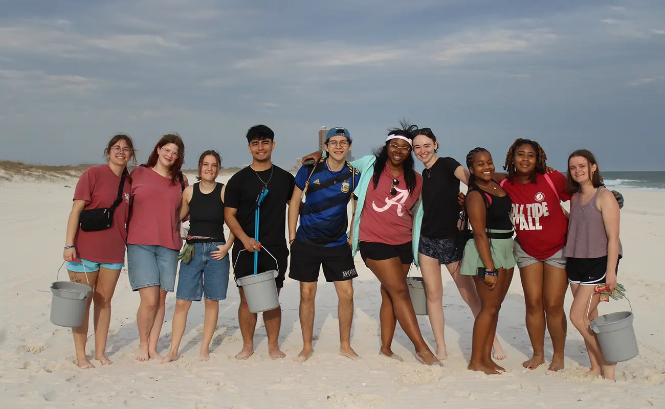 UA Students at the beach with buckets and gloves for beach cleanup during their Beyond Bama 2025 trip