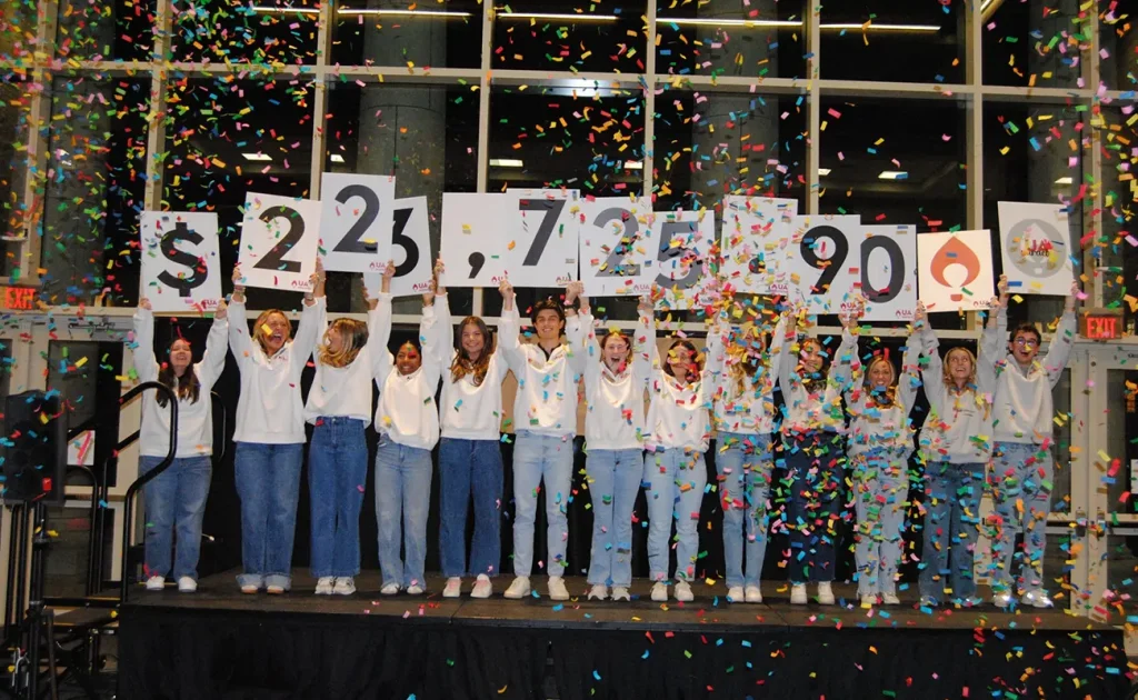 UA students hold up signs revealing the $223,725.90 raised by UA Miracle in 2025 as confetti falls.