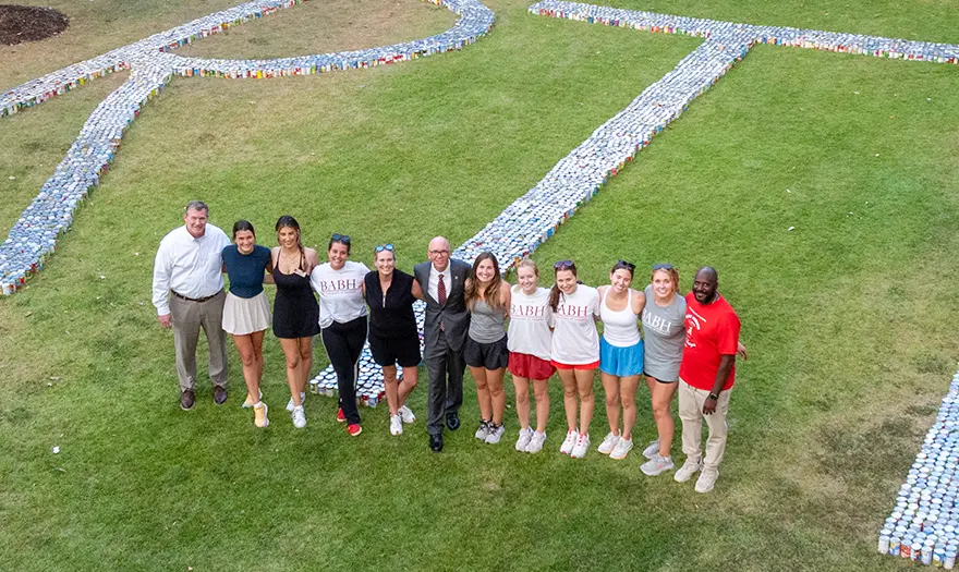 The Beat Auburn Beat Hunger leadership team poses with Dr. Steven Hood and President Peter J Mohler in front of donated canned goods that spell out RTR on the Quad.